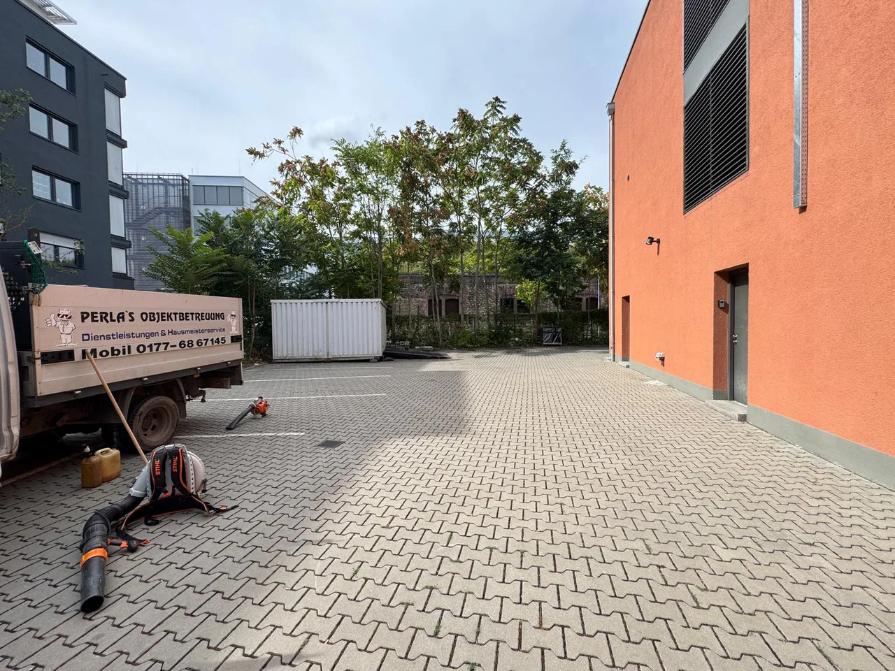 Perla’s Servicefahrzeug und Arbeitsgeräte bei der Objektbetreuung in einem Innenhof